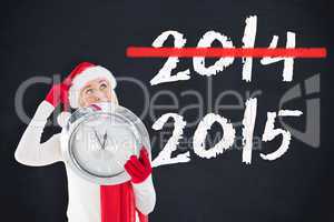 Composite image of festive blonde holding a clock