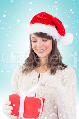 Composite image of festive brunette opening a gift