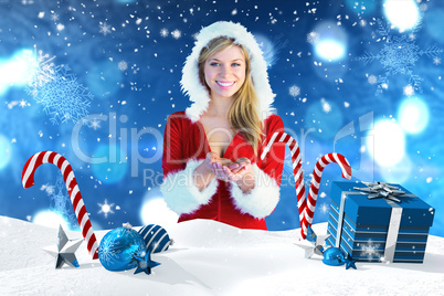 Composite image of pretty girl holding hands out in santa outfit