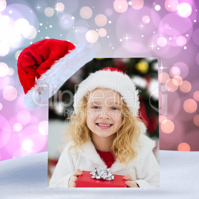 Composite image of festive little girl holding a gift