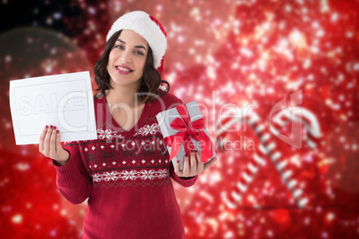 Composite image of brunette holding gift and sale sign