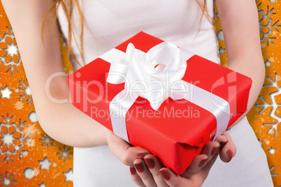 Composite image of woman holding red and white gift