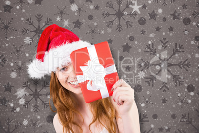 Composite image of festive redhead holding a gift