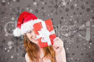 Composite image of festive redhead holding a gift