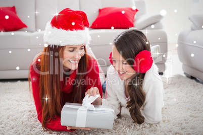 Composite image of festive mother and daughter opening a christm