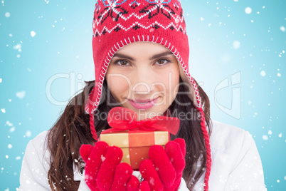 Composite image of smiling brunette in winter clothes holding gi