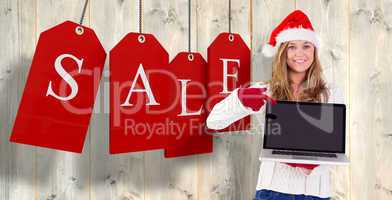 Composite image of festive blonde pointing to laptop