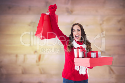 Composite image of excited brunette showing christmas gifts