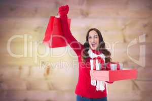 Composite image of excited brunette showing christmas gifts