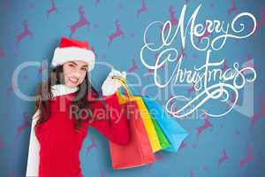 Composite image of festive brunette in winter wear holding shopp