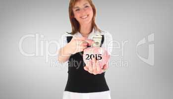 Composite image of woman putting money in a piggy bank