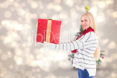 Composite image of festive blonde holding a gift