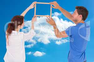 Composite image of couple deciding to hang picture
