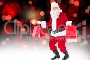 Composite image of smiling santa claus holding shopping bags