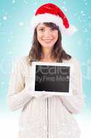 Composite image of festive brunette holding a tablet pc