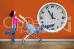 Composite image of young couple having fun with shopping cart