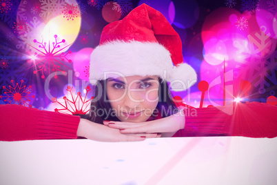 Composite image of pretty brunette in santa hat smiling at camer