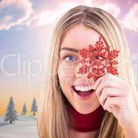 Composite image of happy blonde holding red snowflake