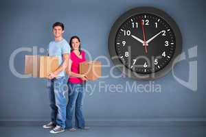 Composite image of young couple holding moving boxes