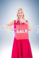 Stylish blonde in red dress showing sale bag