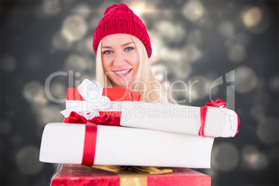 Composite image of festive blonde holding pile of gifts