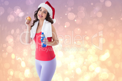 Composite image of festive fit brunette holding bottle and apple