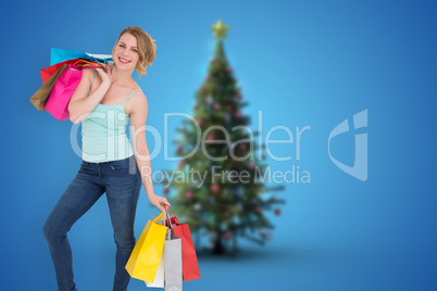 Composite image of smiling blonde woman standing with shopping b Composite image of smiling blonde woman standing with shopping b