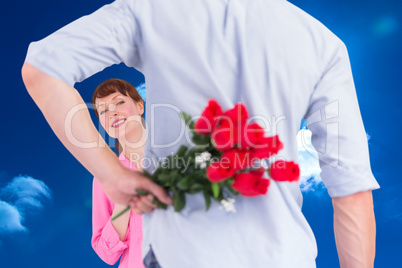 Composite image of man holding roses behind him