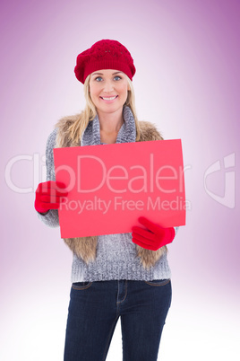 Blonde in winter clothes holding red sign