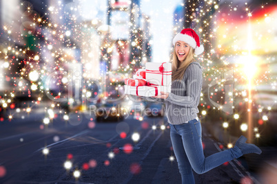 Composite image of festive blonde holding pile of gifts