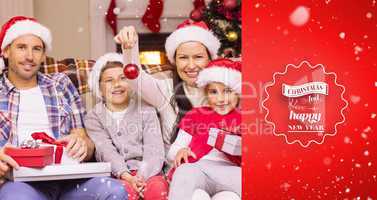 Composite image of happy family wearing santa hat on the couch