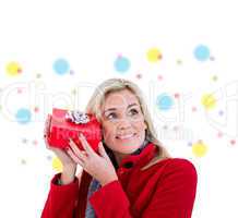 Composite image of festive blonde holding red gift