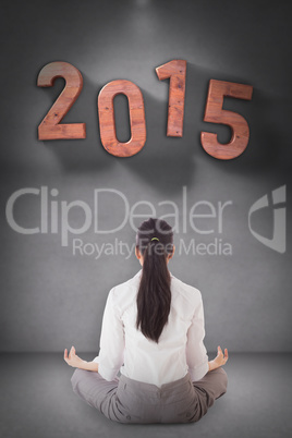 Composite image of businesswoman sitting in lotus pose