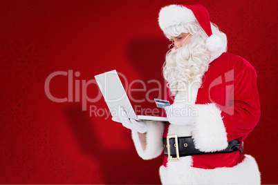 Composite image of santa claus shopping online with laptop