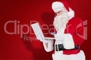 Composite image of santa claus shopping online with laptop