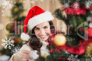 Composite image of beauty brunette decorating a christmas tree