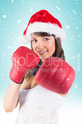 Composite image of festive brunette punching with boxing gloves