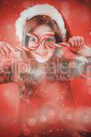 Composite image of happy little girl in santa hat holding candy