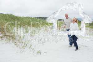 Composite image of cheerful senior couple walking at beach
