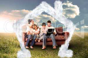 Composite image of happy family using the laptop in a field