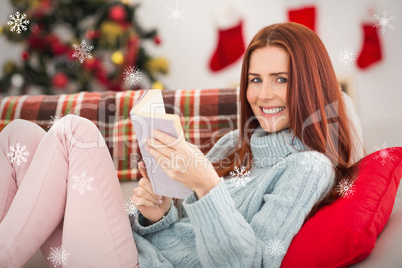 Composite image of festive redhead reading on the couch