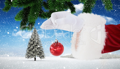 Composite image of santa claus holding red bauble