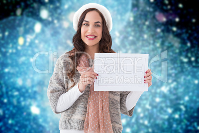 Composite image of brunette in winter clothes holding sale sign