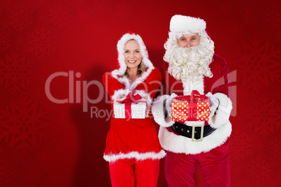 Composite image of santa and mrs claus smiling at camera offerin