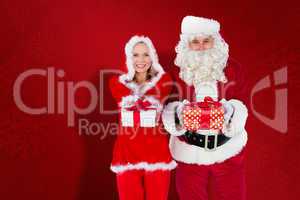 Composite image of santa and mrs claus smiling at camera offerin