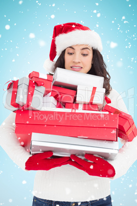 Composite image of stressed brunette in santa hat holding pile o