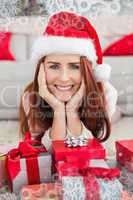 Composite image of festive redhead smiling at camera holding gift