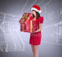 Composite image of surprised festive brunette holding a gift