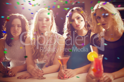 Composite image of attractive friends drinking cocktails togethe