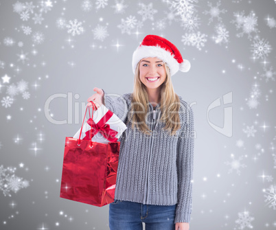 Composite image of festive blonde holding christmas gift and bag